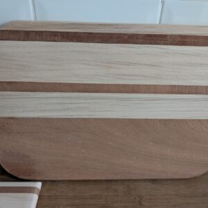Large handcrafted cutting board made from contrasting Oak and Sapele hardwoods, featuring smooth rounded corners and a striped two‑tone design resting on a kitchen worktop